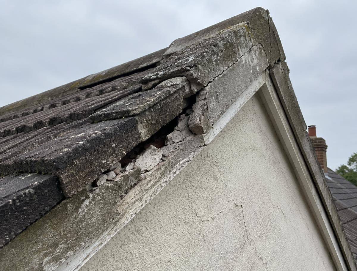 Cracked and crumbling cement verge mortar at the edge of an older tiled roof